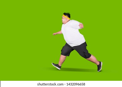 Portrait of a scared fat man running away from something in the studio with green screen - Powered by Shutterstock