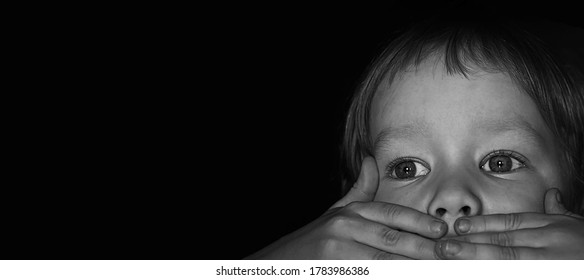 Portrait Of A Scared Little Boy Child. The Kid Covered His Mouth With His Hands. The Concept Of Stuttering, Silence Due To Stress And Shock.