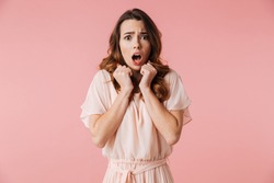 Portrait Of A Scared Young Girl In Dress Looking At Camera Isolated Over Pink Background