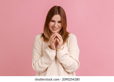 Portrait of scheming blond woman thinking devious plan with cunning face expression, having slyly idea to prank, wearing white sweater. Indoor studio shot isolated on pink background.