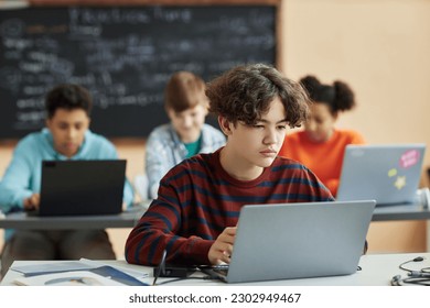 Portrait of school boy using laptop computer in class during programming lesson - Powered by Shutterstock
