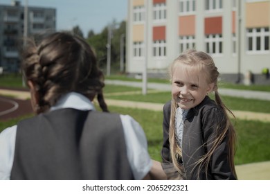 Portrait Of School Girls Talks At Schoolyard, Talking And Laughing During Recess Time In Elementary School. Schoolmates Playing At School Break Outdoors. Back To School Concept.