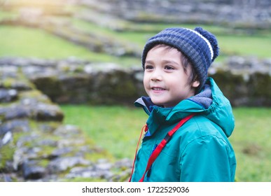 Portrait Of School Kid Explore And Learning About History With School Trip, Happy Child Boy Wearing Hat And Winter Cloths Standing Alone With Blurry Ruins Of Old Abbey Background