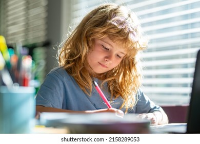 Portrait School Kid Siting On Table Doing Homework. Concentrated Serious Child Writing In Notebook. Focused Schoolboy Studying And Preparing For Exams.