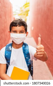 Portrait Of Of School Kid Wearing Protective Face Mask For Pollution Or Virus And Showing Thumbs Up. Coronavirus And School Concept