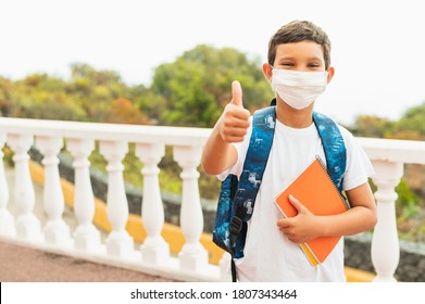 Portrait Of Of School Kid Wearing Protective Face Mask For Pollution Or Virus And Showing Thumbs Up While Waiting For School Bus In The Morning. Coronavirus And School Concept.