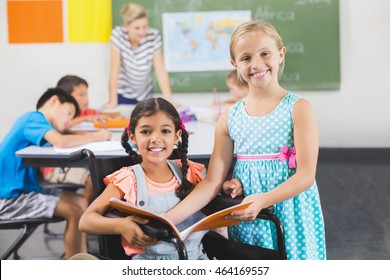 Portrait of school kids holding book in classroom at school