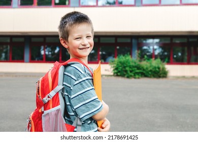 Portrait of a schoolboy boy with a backpack on his back and textbooks in his hands against the school. Back to school. Beginning of the school year - Shutterstock ID 2178691425