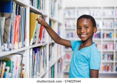 Portrait of schoolboy selecting a book from bookcase in library at school - Powered by Shutterstock