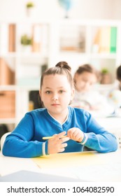 Portrait of schoolgirl sitting at the desk and studying at school - Shutterstock ID 1064082590