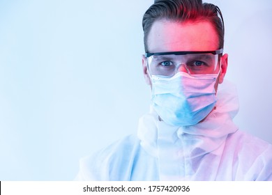 Portrait Of Scientist In PPE Suit And Wearing Mask And Goggles With Dramatic Lighting.