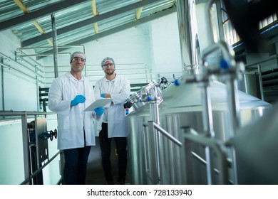 Portrait of scientists with clipboard standing by storage tank in factory - Shutterstock ID 728133940