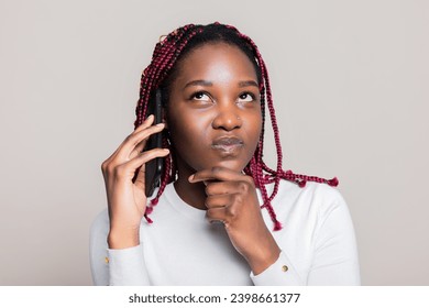 Portrait selective focus close up shot of African American woman with braids holding hand near face talking on phone showing confused thoughtful emotions thinking. - Powered by Shutterstock