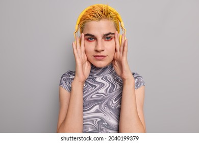 Portrait Of Self Confident Hipster Girl Keeps Hands Near Face Looks Directly At Camera Has Unique Appearance Stands Out From Crowd Enjoys Listening Favorite Rock Song In Headphones. Teenage Lifestyle