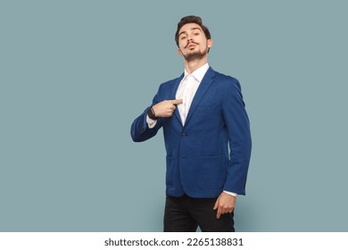 Portrait of self confident proud man with mustache standing pointing at himself, looking at camera with pride, wearing white shirt and jacket. Indoor studio shot isolated on light blue background. - Shutterstock ID 2265138831