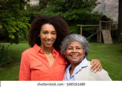 Portrait of senior African American woman with her daughter in the garden, smiling to camera and embracing. Family enjoying time at home, lifestyle concept