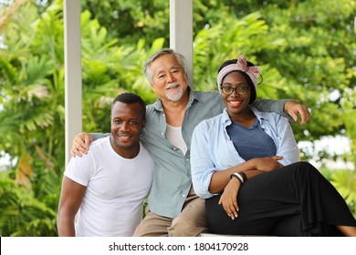 Portrait Of Senior Asian Uncle With Young Couple Of Black African American Who Live Happily And Peacefully In The Same Green Environment Neighborhood 