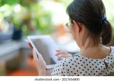 portrait of senior asian woman using tablet to play social media at home garden. elderly and technology concept - Powered by Shutterstock