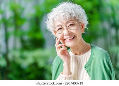 portrait of senior asian woman wearing eye glasses by the garden - Shutterstock ID 2207400713