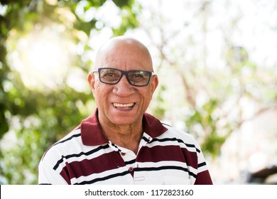 Portrait Of Senior Brazilian Black Man With Glasses Looking At Camera In Sunset And Smiling. Horizontal Shape, Copy Space