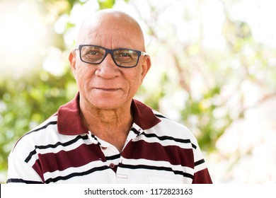 Portrait Of Senior Brazilian Black Man With Glasses Looking At Camera In Sunset And Smiling. Horizontal Shape, Copy Space