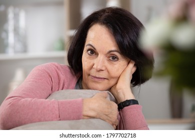 Portrait Of A Senior Brunette Woman Sat On The Sofa