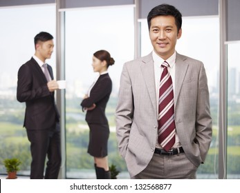 Portrait Of A Senior Business Executive With His Colleagues In The Background.