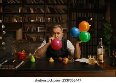 Portrait of senior business man blowing up balloon for success celebration