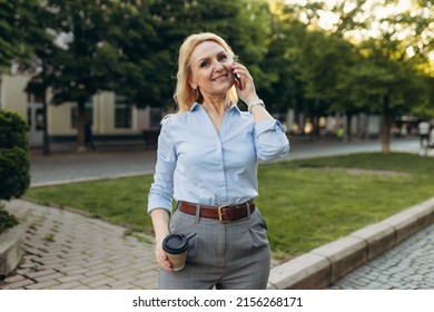 Portrait Of Senior Business Woman Hold The Paper Cup And Talking Phone In The City. Happy Mature Business Woman 50s