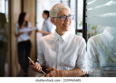 Portrait of senior business woman holding digital tablet while standing at office. - Powered by Shutterstock