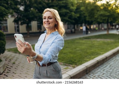 Portrait Of Senior Business Woman Using Smartphone In The City. Cheerful Mature Business Woman In Classic Wear