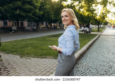 Portrait Of Senior Business Woman Using Smartphone In The City. Cheerful Mature Business Woman In Classic Wear