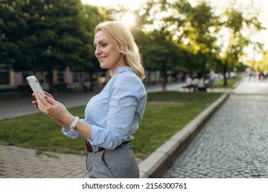 Portrait Of Senior Business Woman Using Smartphone In The City. Cheerful Mature Business Woman In Classic Wear