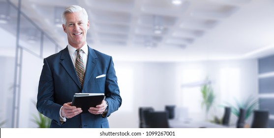 Portrait eines Geschäftsmanns, der Tablet vor seinem modernen Büro benutzt