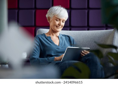 Portrait of senior businesswoman sitting on lounge chair using digital tablet - Powered by Shutterstock