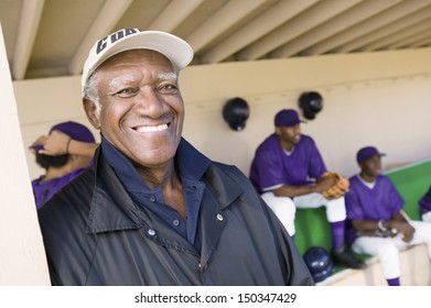 Portrait of senior coach smiling with players in background - Powered by Shutterstock