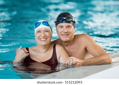 Portrait Of A Senior Couple Bathing In Swimming Pool And Looking At Camera. Smiling Mature Man And Old Woman Enjoying Time Together In A Swimming Pool. Happy Retired Couple After Aqua Fitness.