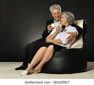 Portrait Of A Senior Couple With Cap Of Coffee Over A Black Background