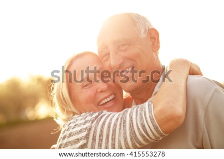 Portrait of senior couple embracing each other in countryside.