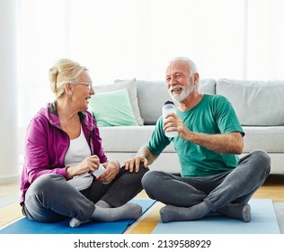 Portrait Of A Senior Couple  Holding Water Bottle And Exercise Mat Smiling And Talking At Home Healthy Living