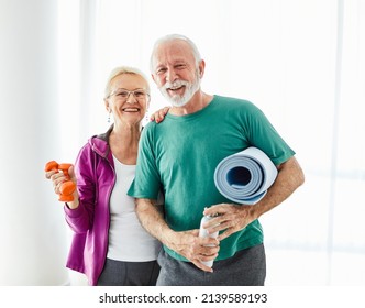 Portrait Of A Senior Couple  Holding Water Bottle And Exercise Mat Smiling And Posing At Home Healthy Living