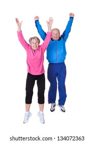 Portrait Of Senior Couple Jumping In Joy Over White Background