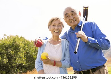 Portrait Of Senior Couple In Park, Holding Croquet Mallet And Balls