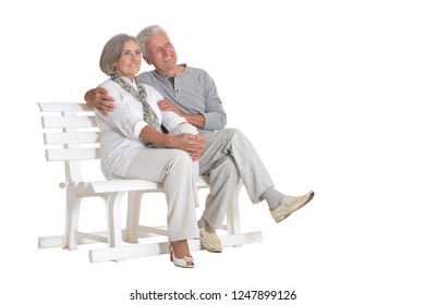 Portrait Of Senior Couple Sitting On Bench On White Background