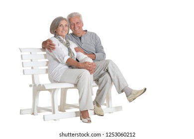 Portrait Of Senior Couple Sitting On Bench On White Background