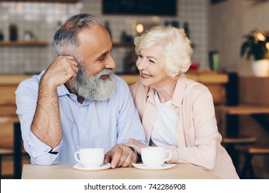 portrait of senior couple sitting at table and drinking coffee in cafe