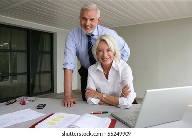 Portrait Of A Senior Couple In Suit In Front Of A Laptop Computer