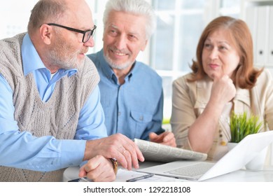 Portrait of senior couples working with laptop and reading newspaper