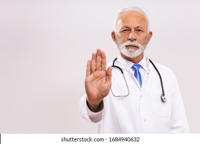 Portrait of senior doctor showing stop sign on gray background. - Powered by Shutterstock