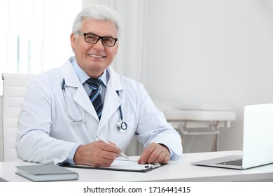 Portrait Of Senior Doctor In White Coat At Workplace